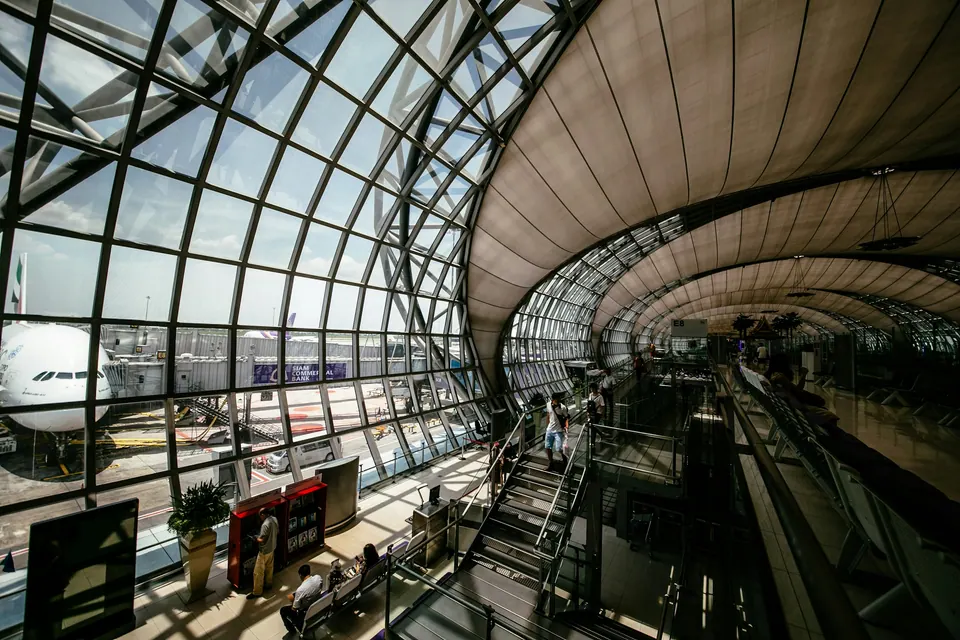 Passengers and walkways beneath the curved glass roof of an airport terminal