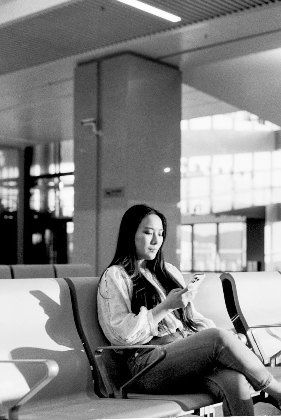 A traveler seated with a phone in an airport waiting area