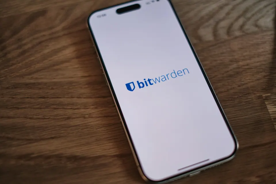 A phone displaying the Bitwarden opening screen on a wooden table