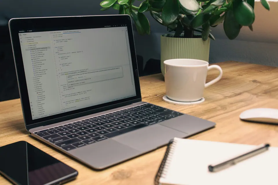 Laptop, phone and open notebook arranged on a wooden desk