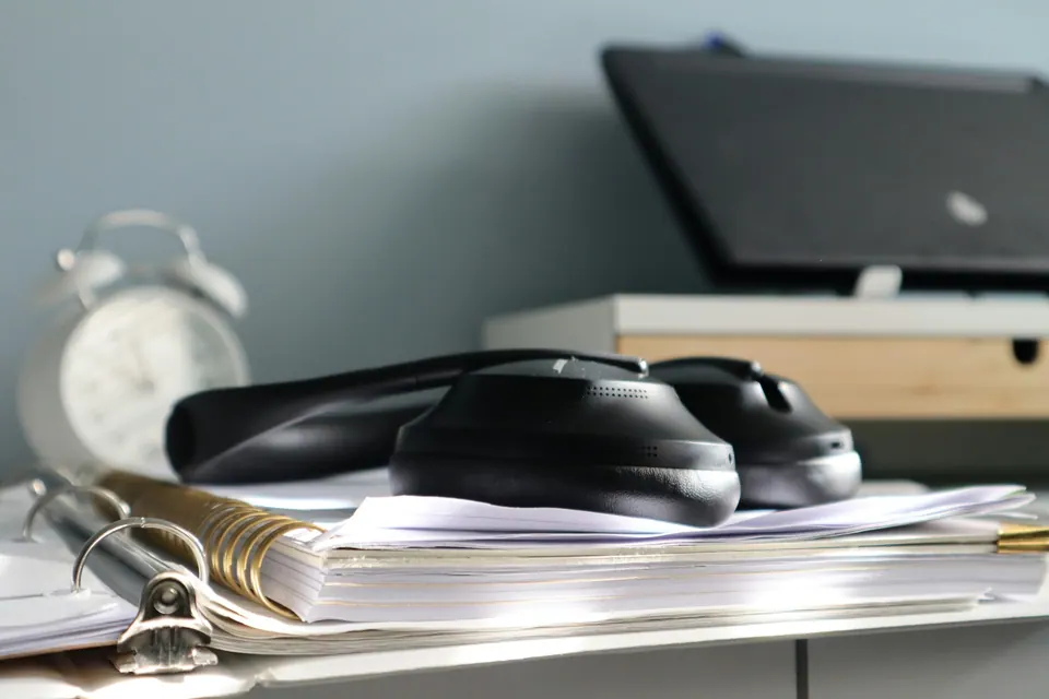 Headphones resting on notebooks with a laptop on a stand behind them