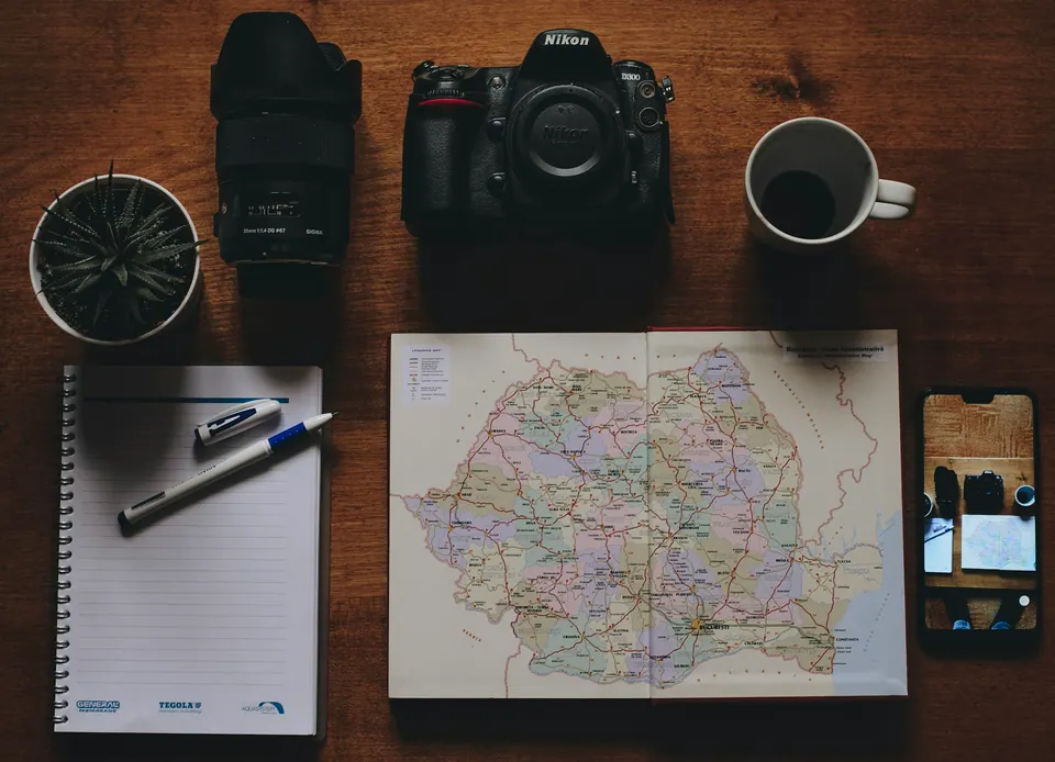 A phone, camera, notebook and mug arranged on a paper map of Germany