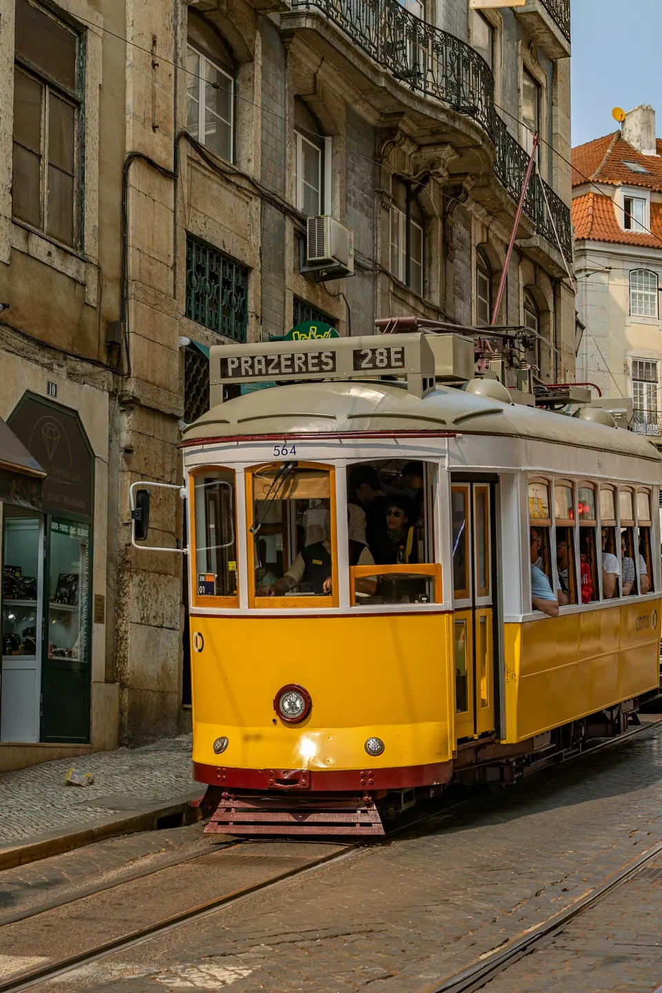 A yellow Lisbon tram passing historic stone buildings
