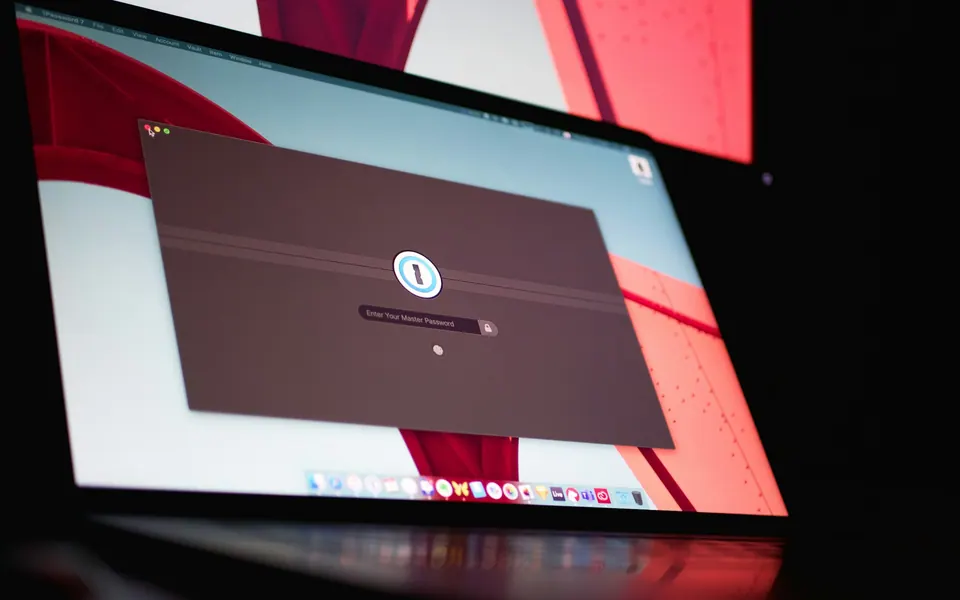 A MacBook displaying the 1Password unlock window in red ambient light