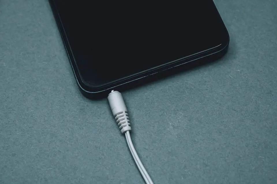 A charging cable connected to a phone on a dark surface