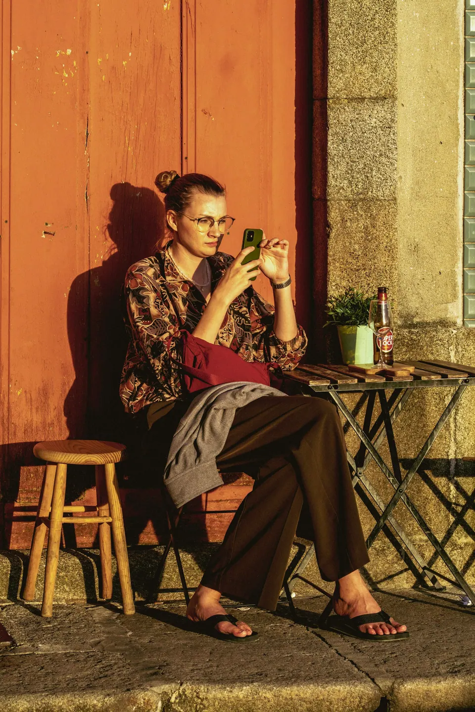 A woman using a phone outside a café in Porto