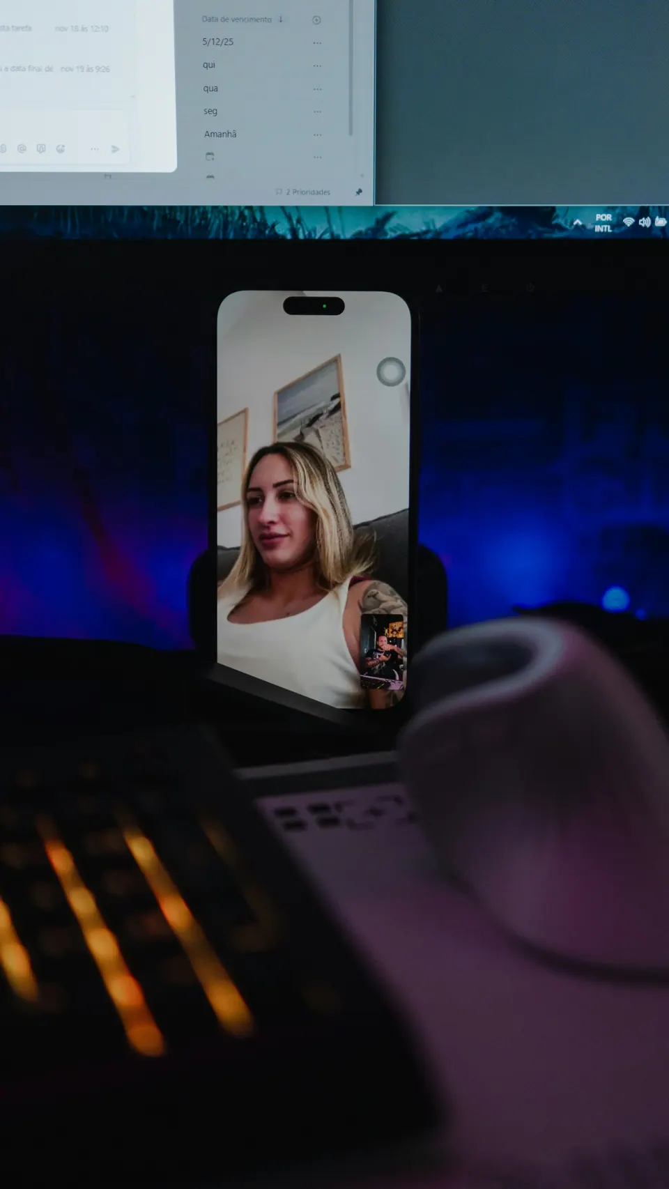 A phone displaying a video call beside a laptop in blue light