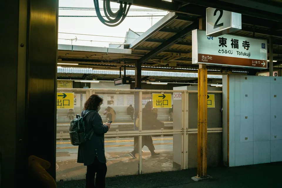 A traveler checking a phone on a railway platform