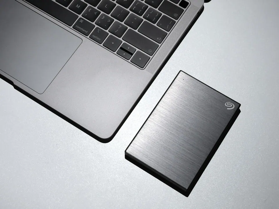 A portable Seagate drive beside a MacBook keyboard