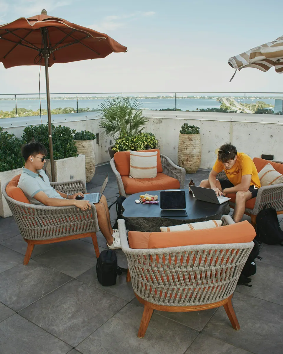 Two people working on laptops around a table on a rooftop terrace
