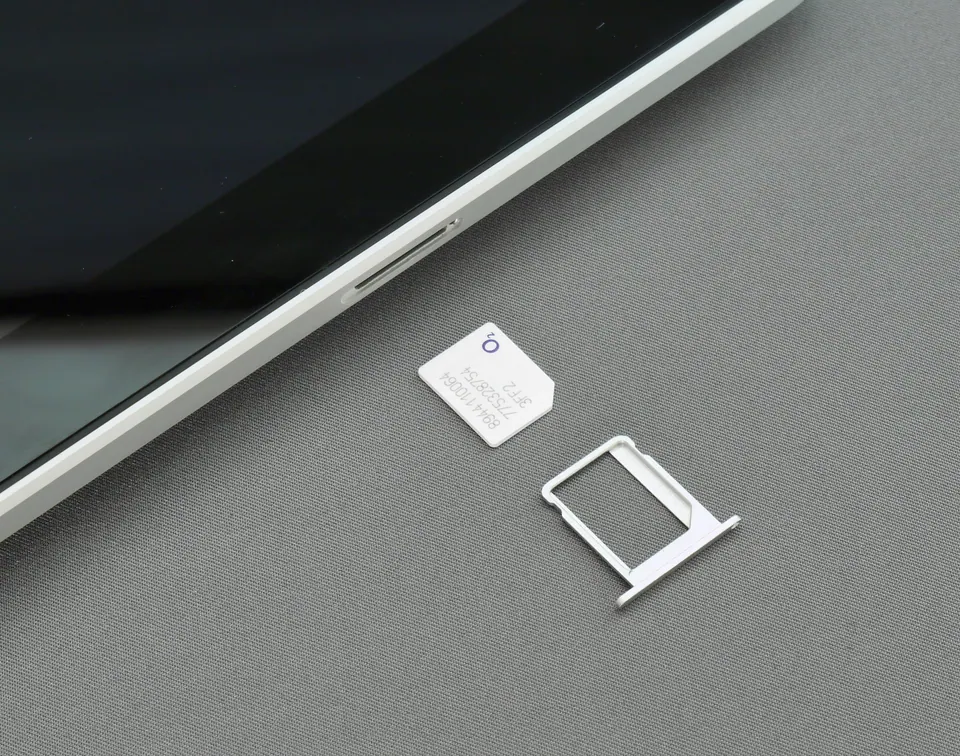 A physical SIM card and its tray beside the edge of a phone