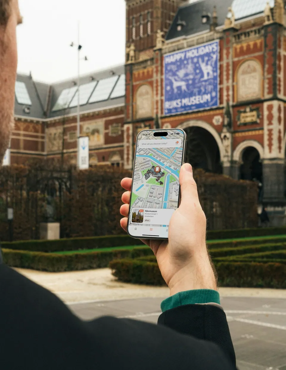 A person consulting a map on a phone beside city buildings