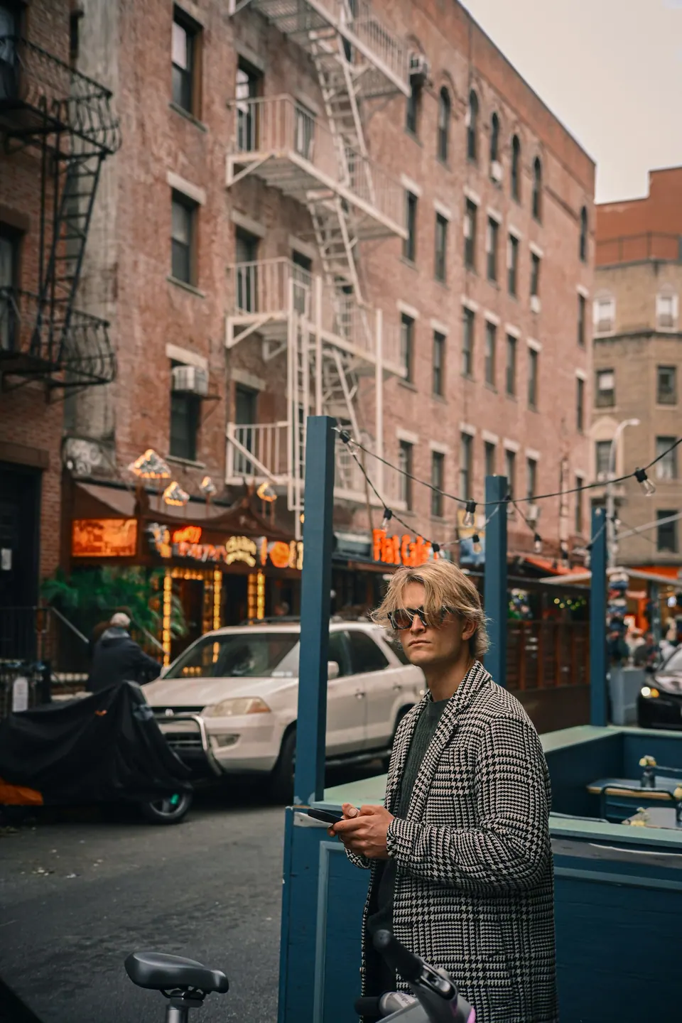 A person holding a phone beside a bicycle on a city street