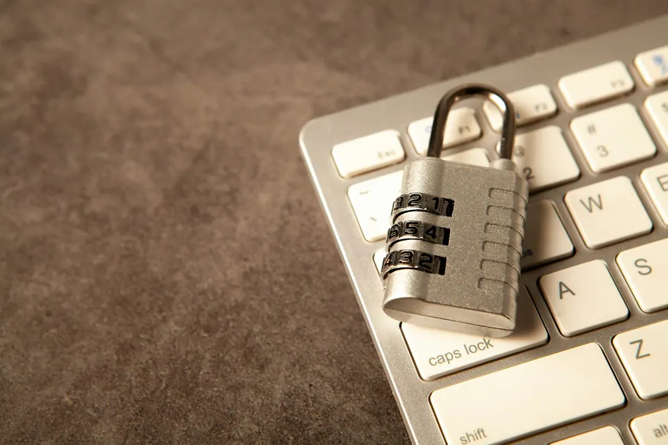 A metal combination padlock resting on a white computer keyboard